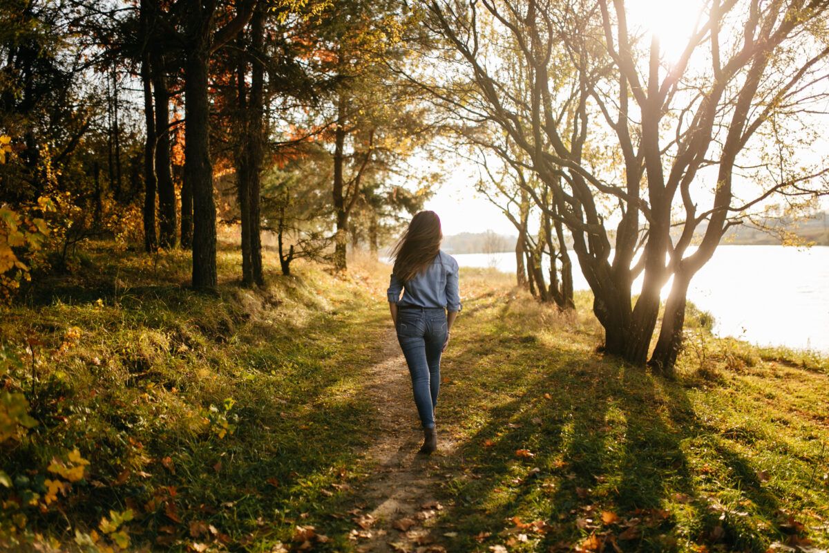 Mujer caminando por un camino natural, simbolizando el proceso de sanación emocional y física.