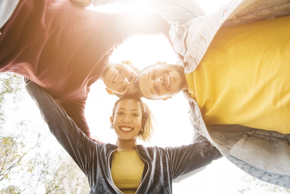 Grupo de amigos sonrientes, bienestar emocional y salud integral con masajes TNDR.